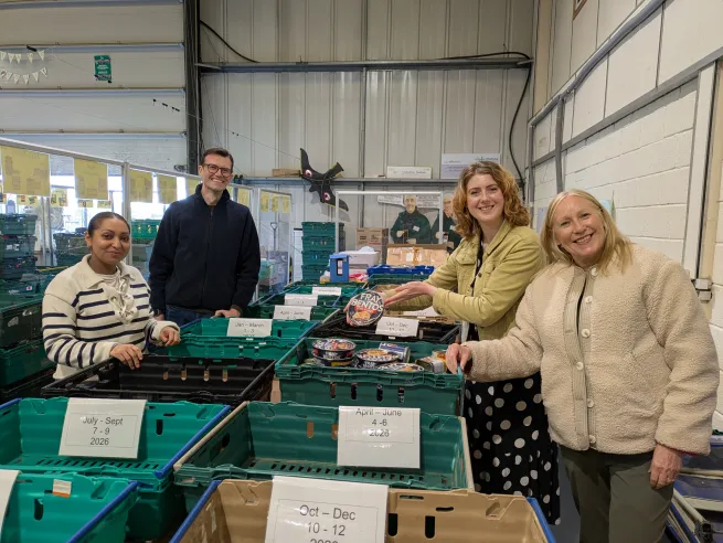 The People's Postcode Lottery sorting team in the warehouse with boxes on the table ready for items