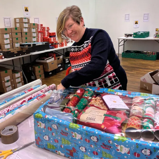 A volunteer wrapping a Christmas hamper