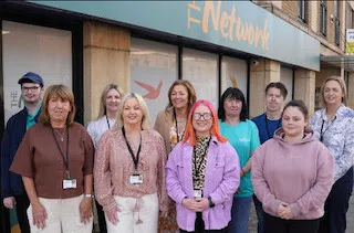 10 people stand in front of The Network building