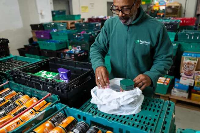 A man sorting food donations in a food bank warehouse