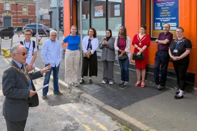 Members of the community advice hub stand outside the building on its opening, local government official giving speech