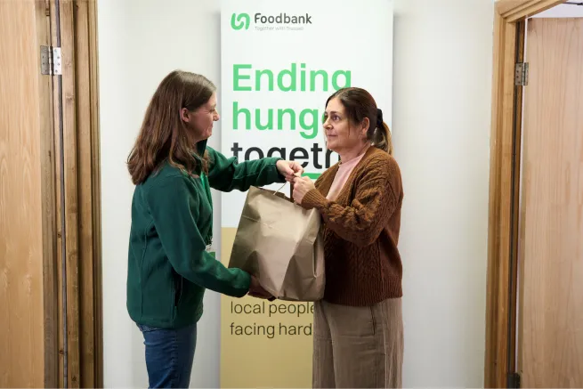 Food bank worker gives woman a food parcel in food bank