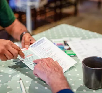 Arms of one person handing another a leaflet