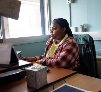 A foodbank volunteer working at a computer desk.