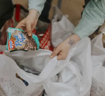 Hands are looking through the content of an emergency food parcel in plastic bags