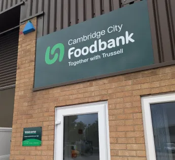 Large dark green sign reading 'Cambridge City Foodbank' above a white door.