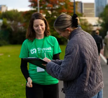 One woman collecting signatures on the street, one woman signing petition