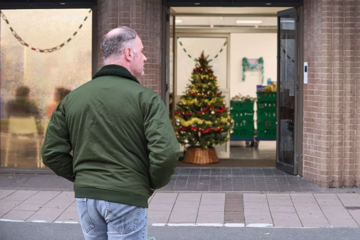 A person walks towards the entrance of a food bank, with a Christmas tree inside.