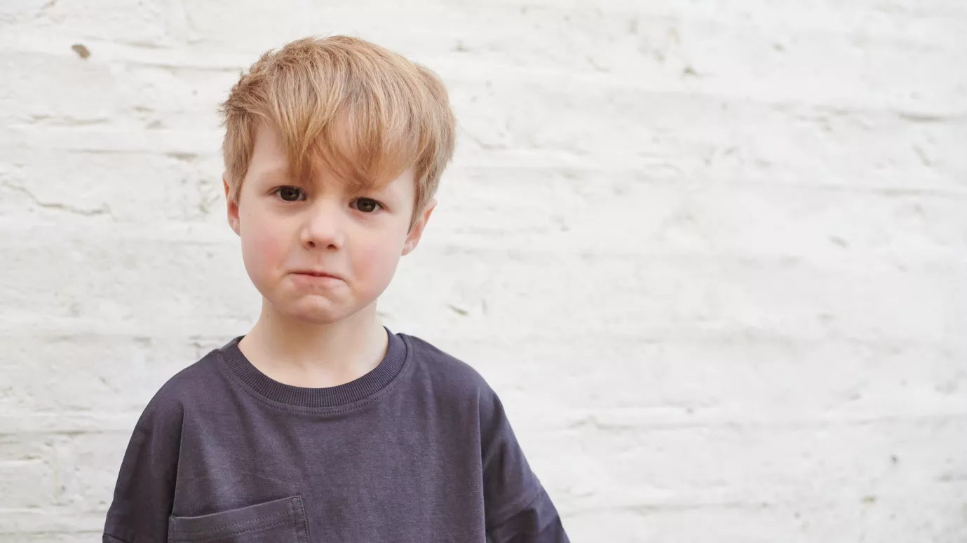 Small boy with blonde hair looking sad
