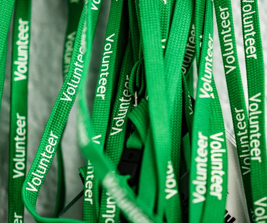 A large number of green lanyards with the text volunteer on them