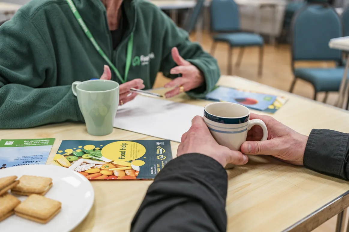 A chat with a cup of tea and biscuits with leaflets on the table