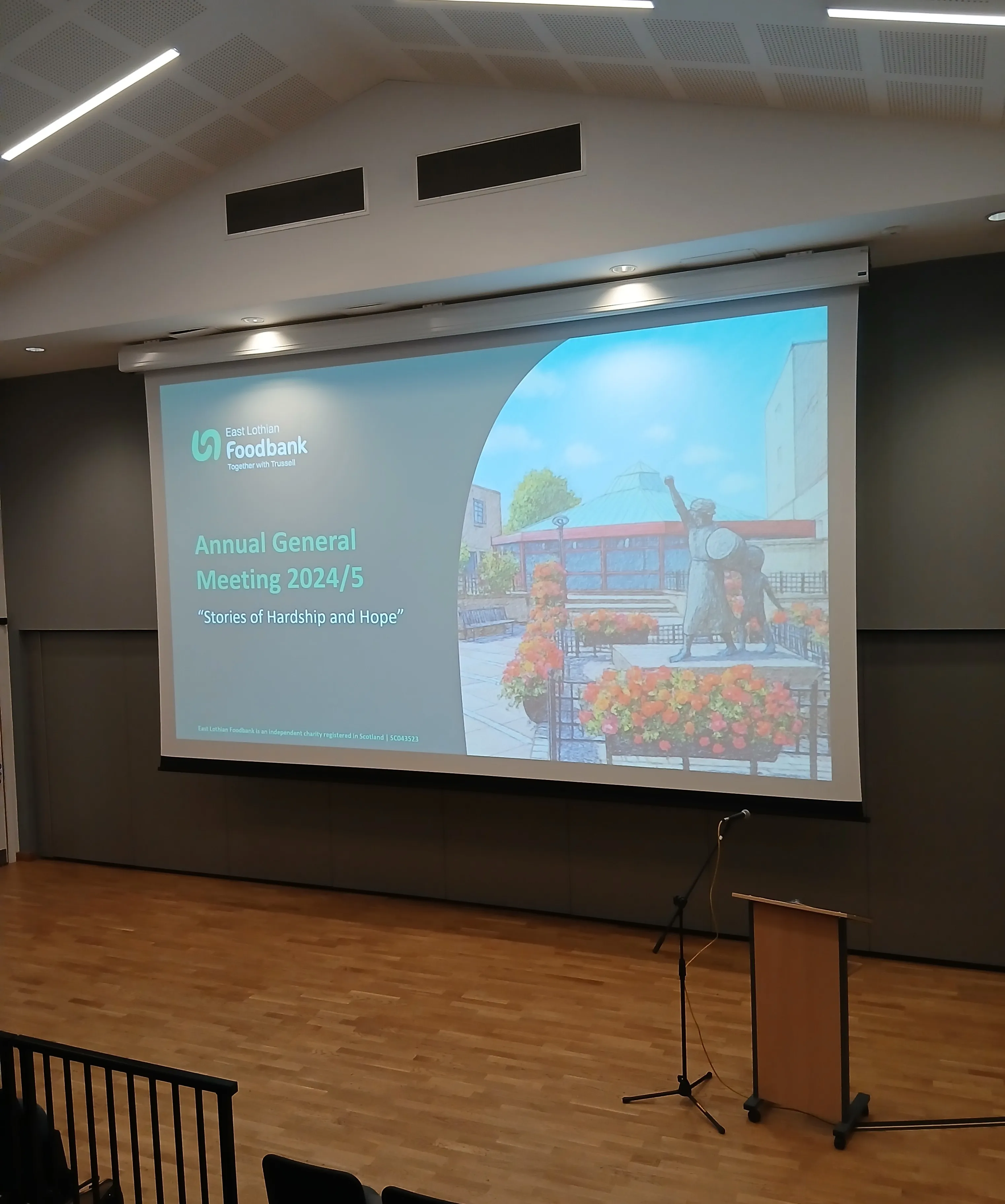 a picture of a hall with a large projection screen with a welcome presentation slide displayed