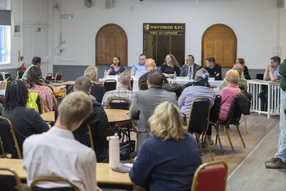 Six candidates and the Foodbank CEO sat at the head of a large, busy room, answering questions.