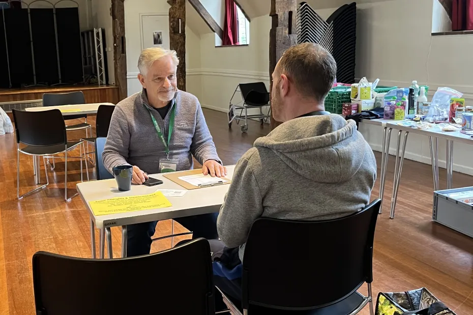 A Foodbank volunteer sat speaking to a client come to collect his food.