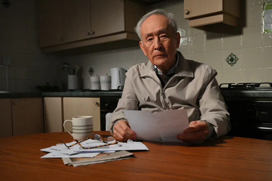 Man sat at kitchen table going through pile of bills