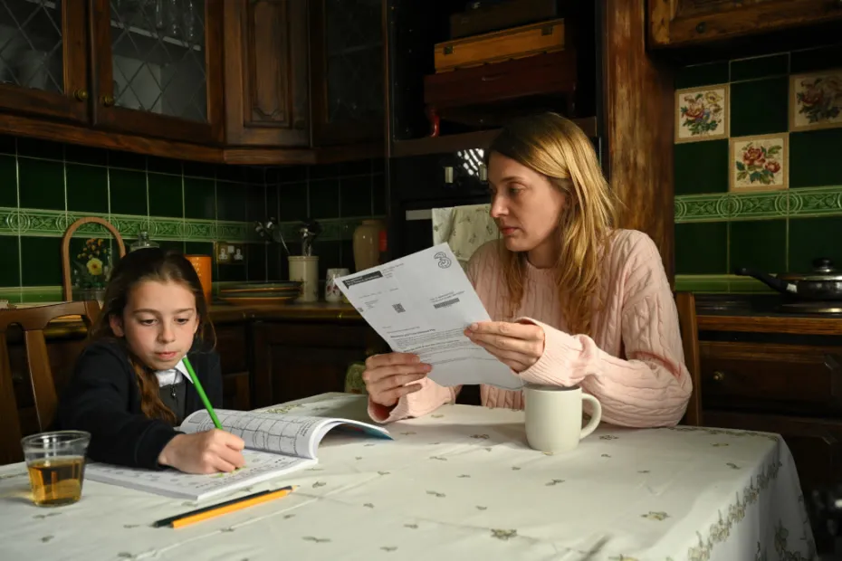 Woman and girl sat at kitchen table doing homework