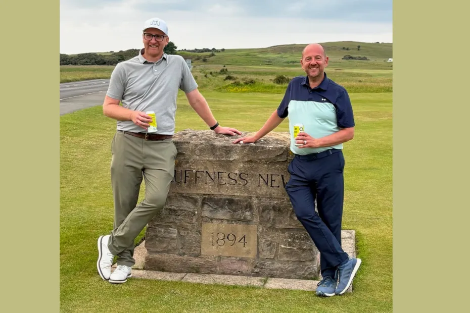 Two men standing by a stone wall