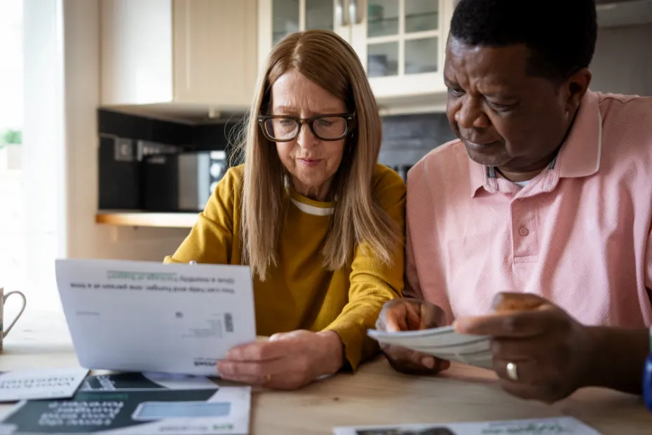 Woman and man sat at kitchen table going through their bills