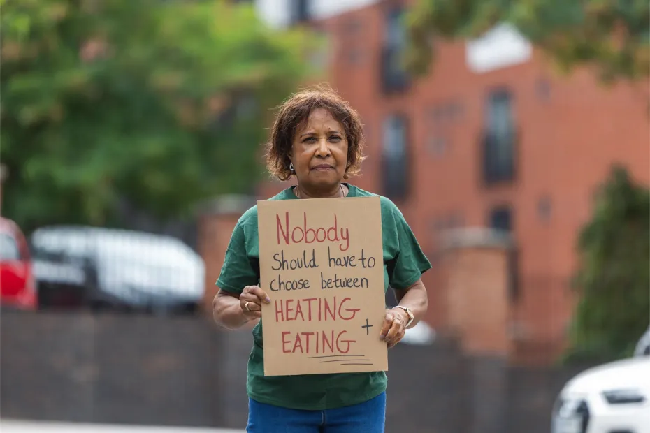 Woman holding a sign saying "Nobody should have to choose between heating and eating"