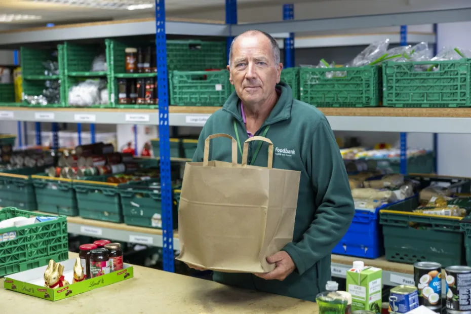 Food bank volunteer holding a food parcel in warehouse