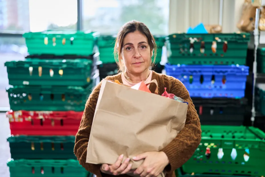Woman holds food parcel in food bank warehouse