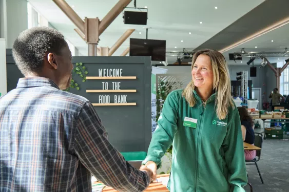 A woman greeting a man by shaking hands at the Bradford foodbank