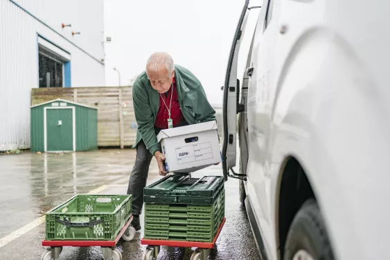 Foodbank volunteer loading crates of food into a van.