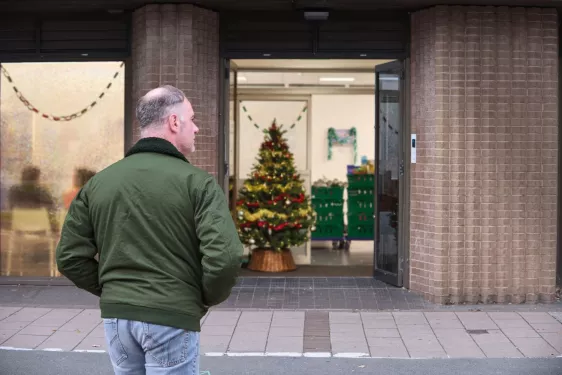 A person walks towards the entrance of a food bank, with a Christmas tree inside.