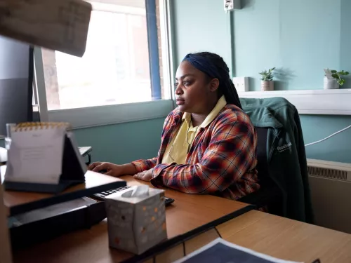 A foodbank volunteer working at a computer desk.