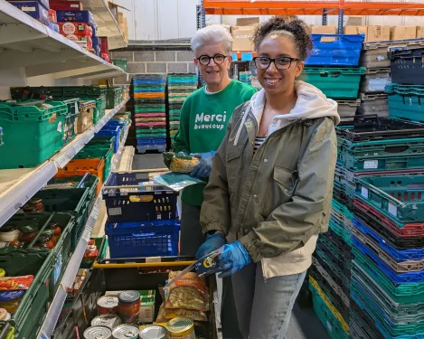 Two People's Postcode Lottery volunteers in the warehouse packaging up items into boxes
