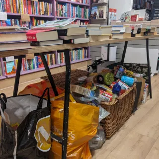 a table with books on top and bags of donated food underneath