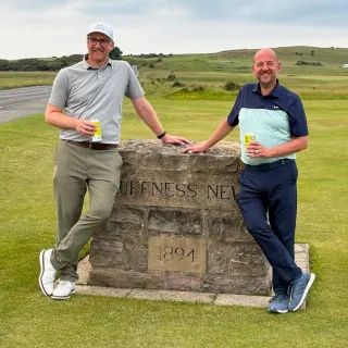 two men standing by a stone wall