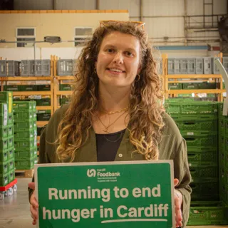 Sophie Bell holding a sign "Running to end hunger in Cardiff"