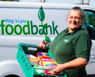 Photo of Warehouse Manager standing in front of the Foodbank van holding a tray of food