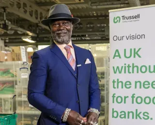 One of Trussell's Ambassadors, Levi Roots, standing by a sign sharing our vision of A UK without the need for food banks