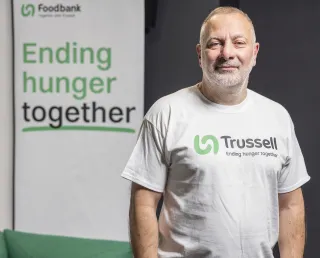 Jed Mercurio, Trussell's Ambassador standing by a sign saying ending hunger together and wearing the Trussell logo on his T-shirt