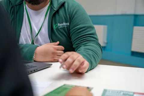 A mid body shot of a volunteer sitting down speaking to a client 