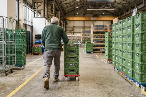 A man pushing a trolley full of food containers inside the Cardiff food bank warehouse