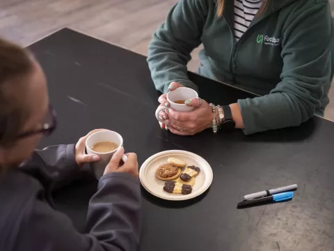 Two people having a cup of tea with some biscuits