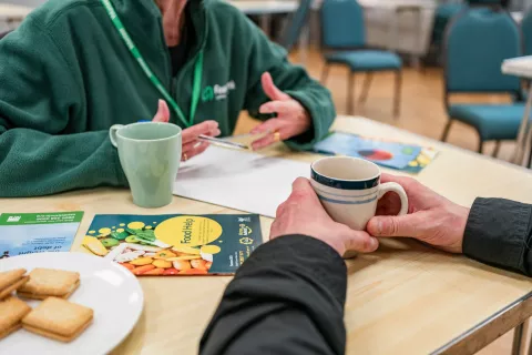 Arms of two people sharing a cup of tea at a table