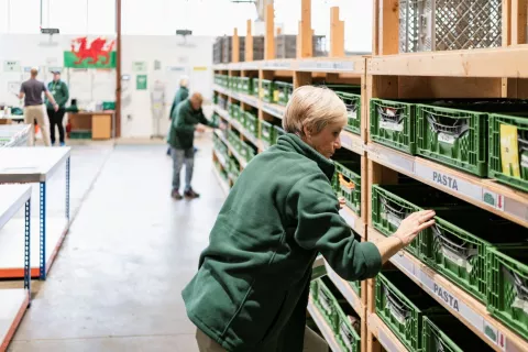 A food bank volunteer sorts through donations on a shelf