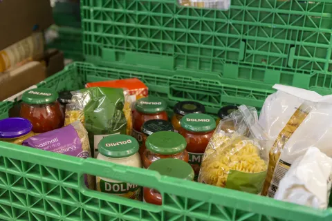 A close up of dried packets of pasta and jars of pasta sauces in a green crate at the Salisbury food bank warehouse.