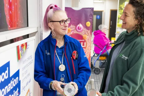 A Tesco staff member and Trussell volunteer stand and chat by food donations