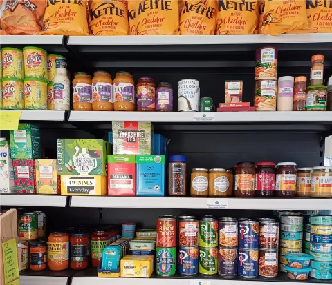 Shelves stacked with jars, tins, crisps, tea, coffee and jam.