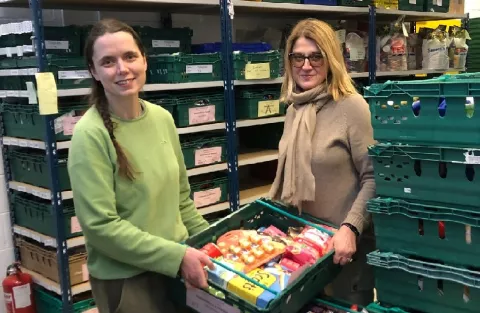 Two people holding a crate in the foodbank warehouse