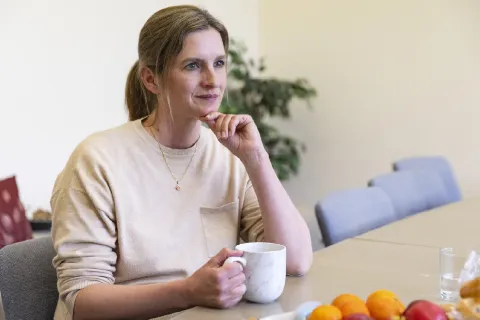 Woman sitting with a thoughtful expression drinking a hot drink from a mug