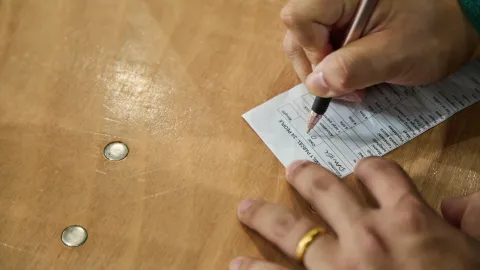 Writing on a receipt with two 5ps on the table