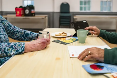 A chat with a cup of tea and biscuits with leaflets on the table