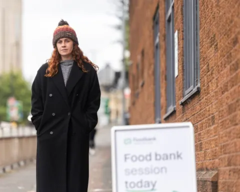 A woman in winter clothing stands outside a food bank