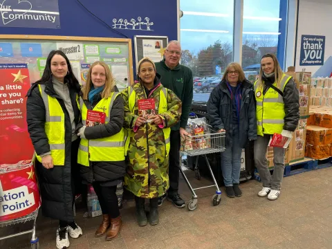 Volunteers stand in a Tesco store welcoming shoppers at a previous food collection